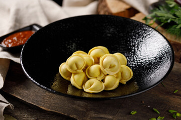 Delicious traditional Russian dumplings, handmade dough with turmeric. Still life on a wooden board. Close-up.