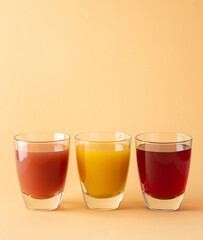 Delicious sweet citrus, mango and pomegranate juices in glass glasses isolated on beige background