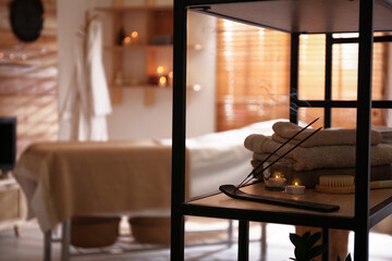 Aromatic incense sticks, burning candles and towels in spa salon. Interior design