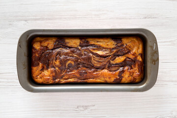 Homemade Chocolate Banana Bread on a rustic wooden board on a white wooden background, top view. Flat lay, overhead, from above.