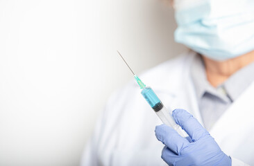 The doctor holds the syringe for the vaccine on white background with space for text.