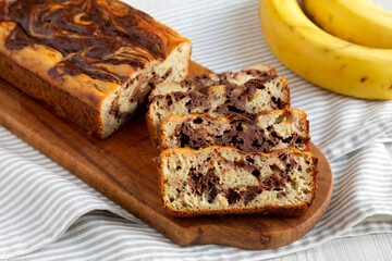 Homemade Chocolate Banana Bread on a rustic wooden board on a white wooden background, side view.