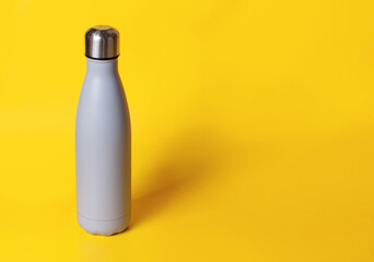 Grey reusable steel bottle on yellow background