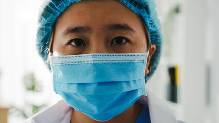 Young Asia lady doctor or nurse worker surgeon preparing for surgical operation and tired opens eyes and looking at camera at health hospital office. Social distancing, quarantine for coronavirus.