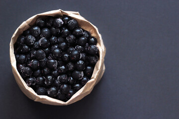 paper bag with black berries close-up on black background