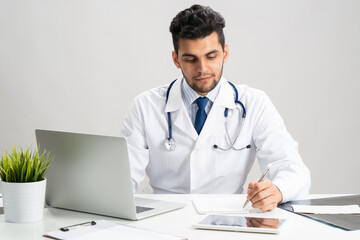 Handsome doctor sitting at desk in office