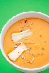 Pumpkin soup with eringi mushrooms in a white plate on a green background. Close-up. Photo for clipping, for the menu