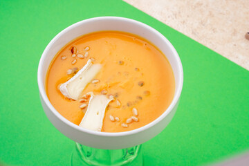 Pumpkin soup with eringi mushrooms in white plate on green background. Close-up. Top view. Space for text. Photo for cutting, for menu