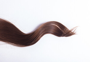 a lock of natural brunette hair on a white background