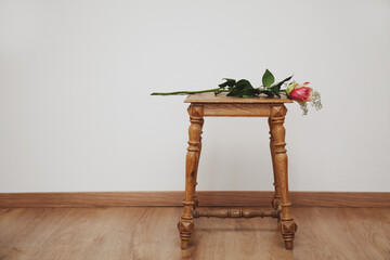 Einzelne Rose mit Schleierkraut auf Holzhocker