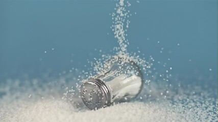 Super slow motion drop salt on a salt shaker, on a blue background. Filmed on a high-speed camera, 1000 fps.  - Powered by Adobe
