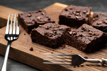 Vegan chocolate brownies with dry srawberries pieces and choco drops with old silverware on dark background