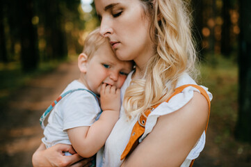 Young mother holding her son in the forest