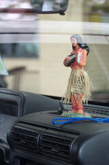 A figurine of a Hawaiian girl with a guitar on the car panel. 