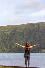 Woman with arms wide open, Sete Cidades landscape, travel Azores.