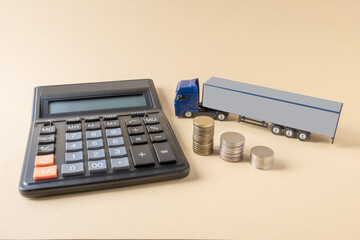 Calculator, mock-up of tractor-trailer, coins placed on light background. Concept. Tariffs, calculation, freight transport costs by truck.