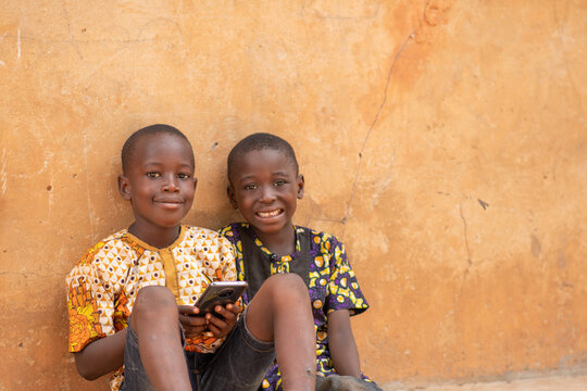 two african kids smiling while using a phone
