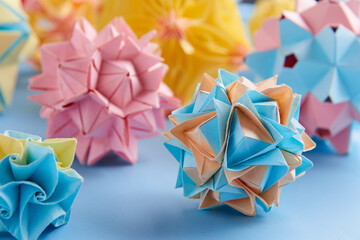 Set of multicolor handmade modular origami balls or Kusudama Isolated on blue background. Visual art, geometry, art of paper folding, paper crafts. Close up, selective focus, copy space.
