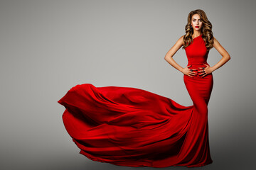 Fashion Woman in Red Tight Dress. Long Evening Red Gown waving on Wind. Beauty Portrait with Long...