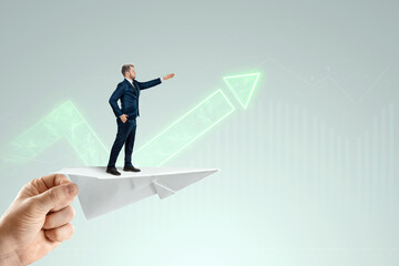 Startup. Businessman flying on a paper airplane with the pushing hand of an investor. Concept for opportunities, investments, business trends, business angels.