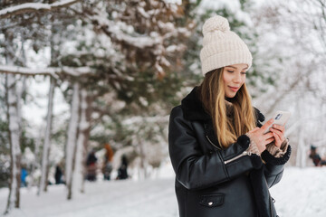 Happy nice girl talking on cellphone while walking in winter forest