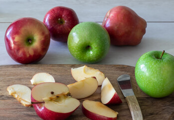 Red and green ripe apples and cut apples on the cutting board