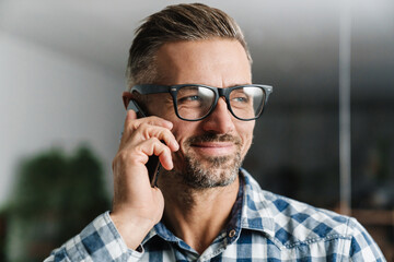 Happy white-haired man smiling while talking on cellphone