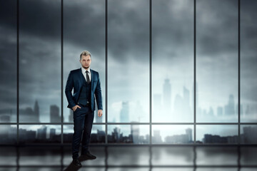 A man in a business suit, a businessman stands against the background of large windows overlooking the city, looks into the distance. Mixed media. Development concept, goals, aspiration.