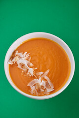 Pumpkin soup in a white plate on a green background. Close-up. Photo for clipping, for the menu