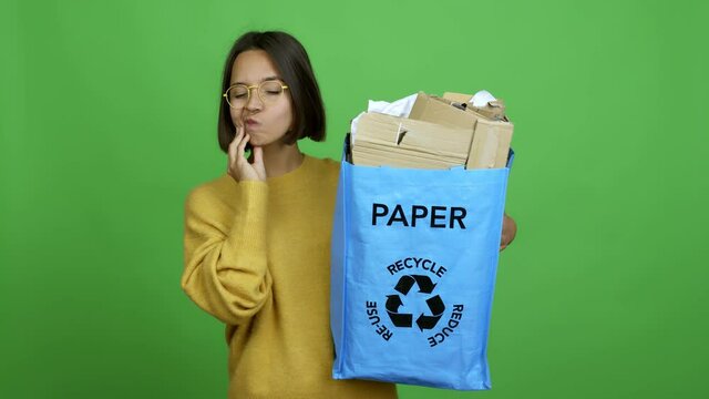 Woman holding a recycling bag full of paper to recycle standing and thinking an idea pointing the finger up over isolated background