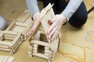 Girl builds a hut from wooden logs, children's wooden constructor