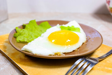 Fried eggs on a plate on the table with a green lettuce leaf.