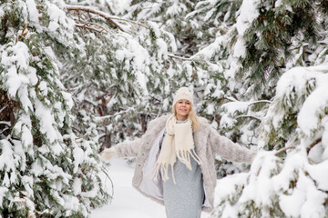 Beautiful young scandinavian caucasian woman on a walk in the forest in winter, among the snowy pine trees
