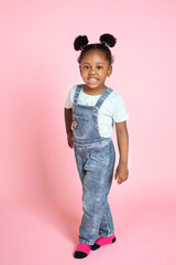 Full length portrait of a cheerful little african girl in trendy casual clothes, with afro hair in...