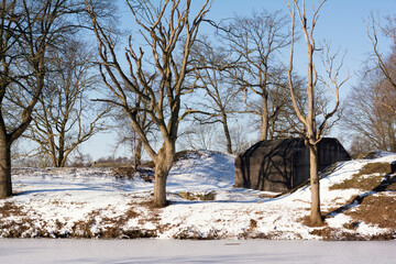 Beautiful winter landscape in the Netherlands, snow, ice, blue sky, bare trees and and a bunker. Ideal environment for walking and enjoying nature