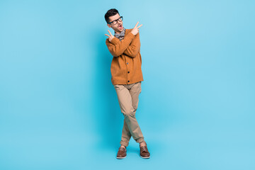 Full length photo of young amazed man dace show v-signs hip hop pose isolated on blue color...
