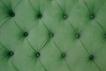 Emerald luxury velour quilted sofa upholstery with buttons, elegant green home decor texture and background. Chesterfield style quilted upholstery backdrop close up. Green pattern texture.