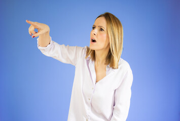 Young woman pointing finger side. Isolated portrait over purple background.