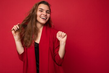 Portrait of positive cheerful fashionable woman in formalwear looking at camera isolated on red...