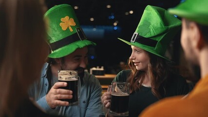 Portrait of friends in Irish hats celebrating Saint Patrick's Day in a pub. Men and women toasting with beer and having fun.