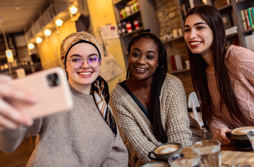Three young multi ethnic women enjoy coffee at a coffee shop.