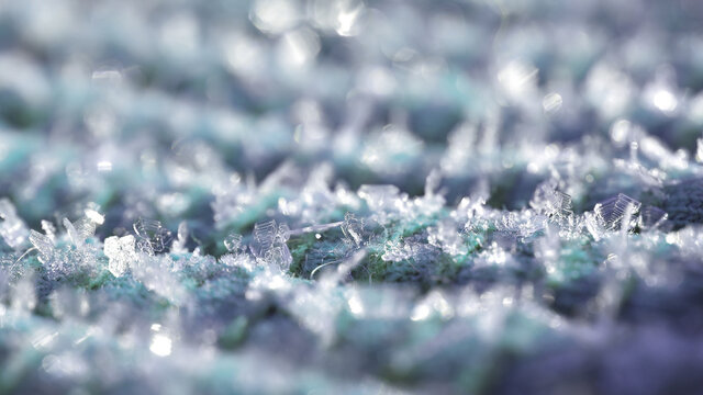 Delicate ice cristals on cyan cold fabric in sunshine as background