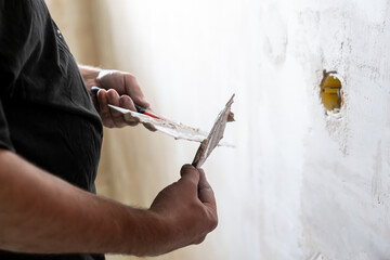 Happy worker man making wall in the room by hand spatula repair