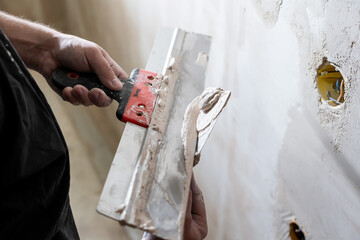Happy worker man making wall in the room by hand spatula repair