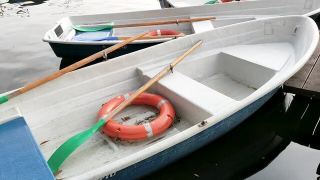 View of boats with oars and lifebuoy that stand at the pier of the lake.