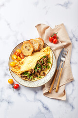 Omelet with champignons and parsley in plate on marble background. Frittata - italian omelet for breakfast or lunch. Flat lay.