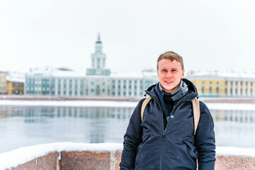 Portrait of a young man in winter on the embankment near the frozen Neva River in St. Petersburg
