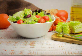 Varied salad, accompanied by small tomatoes. Healthy background and Spanish olive oil. Copy space.