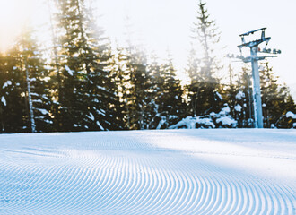 Close up of groomed tracks on a slope in a downhill ski resort on a sunny day. Shallow depth of field.