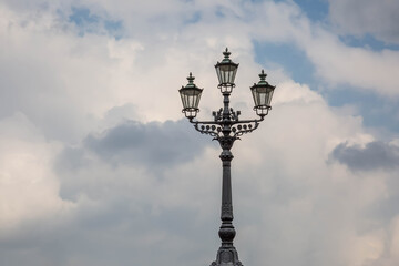 Fototapeta na wymiar Alte Straßenlaterne mit 3 Lampen und bewölktem Himmel